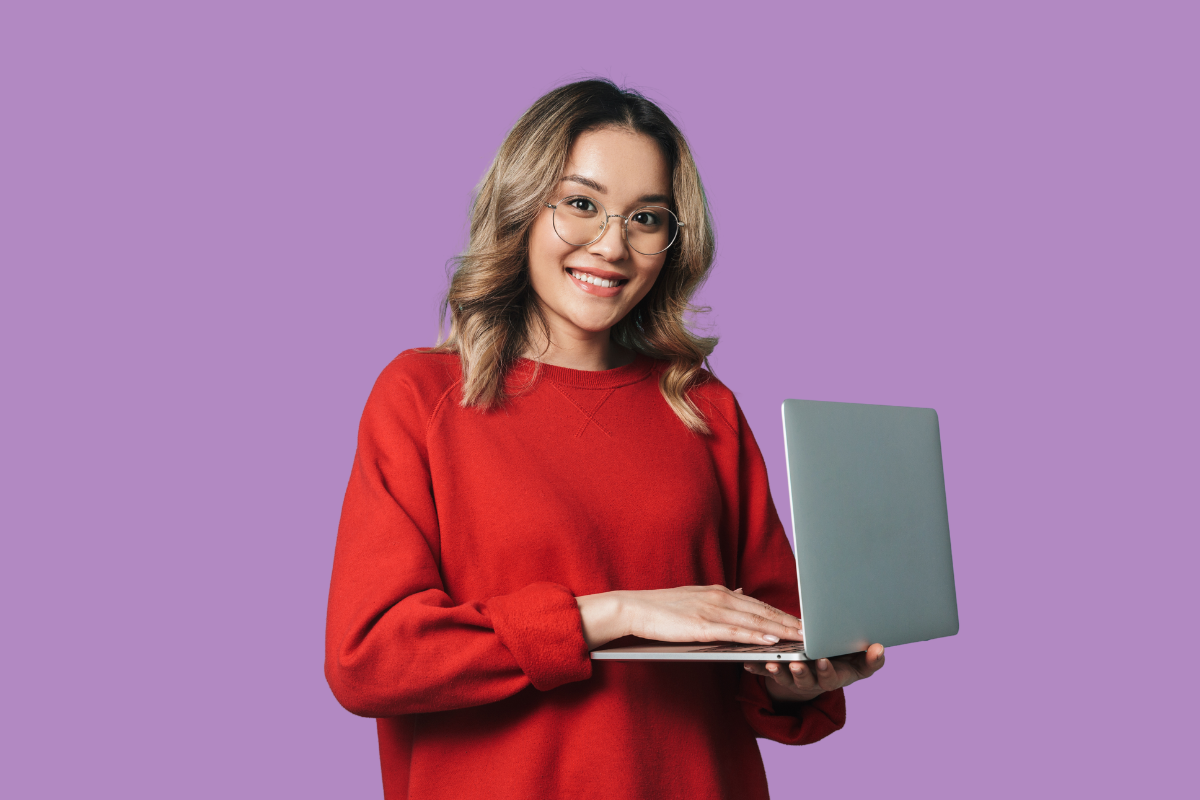 A woman holding a laptop and smiling after successfully contributing to collaborative articles on LinkedIn